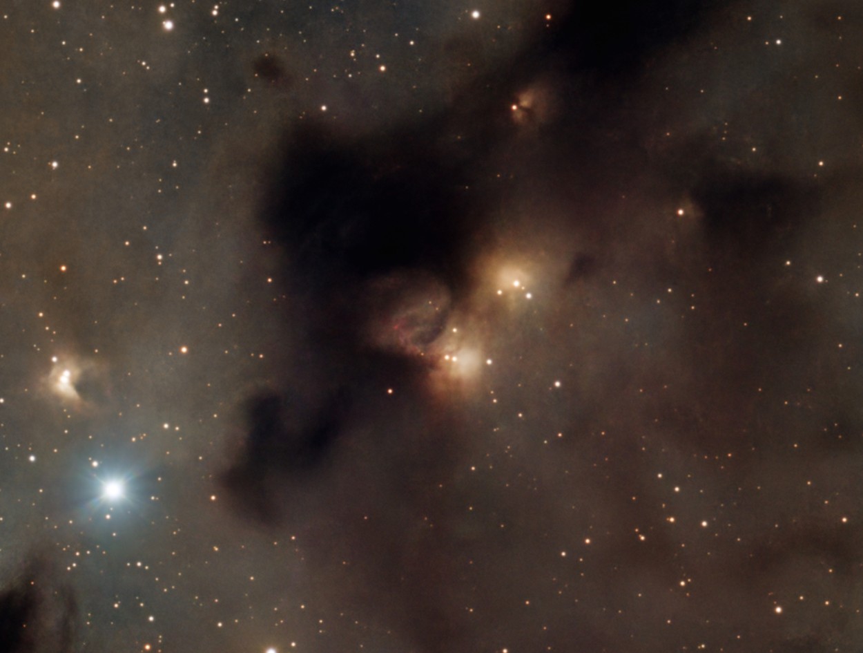 LBN 812 : une poche de formation d'étoiles au cœur du nuage sombre, où de jeunes étoiles éclairent gaz et poussière.