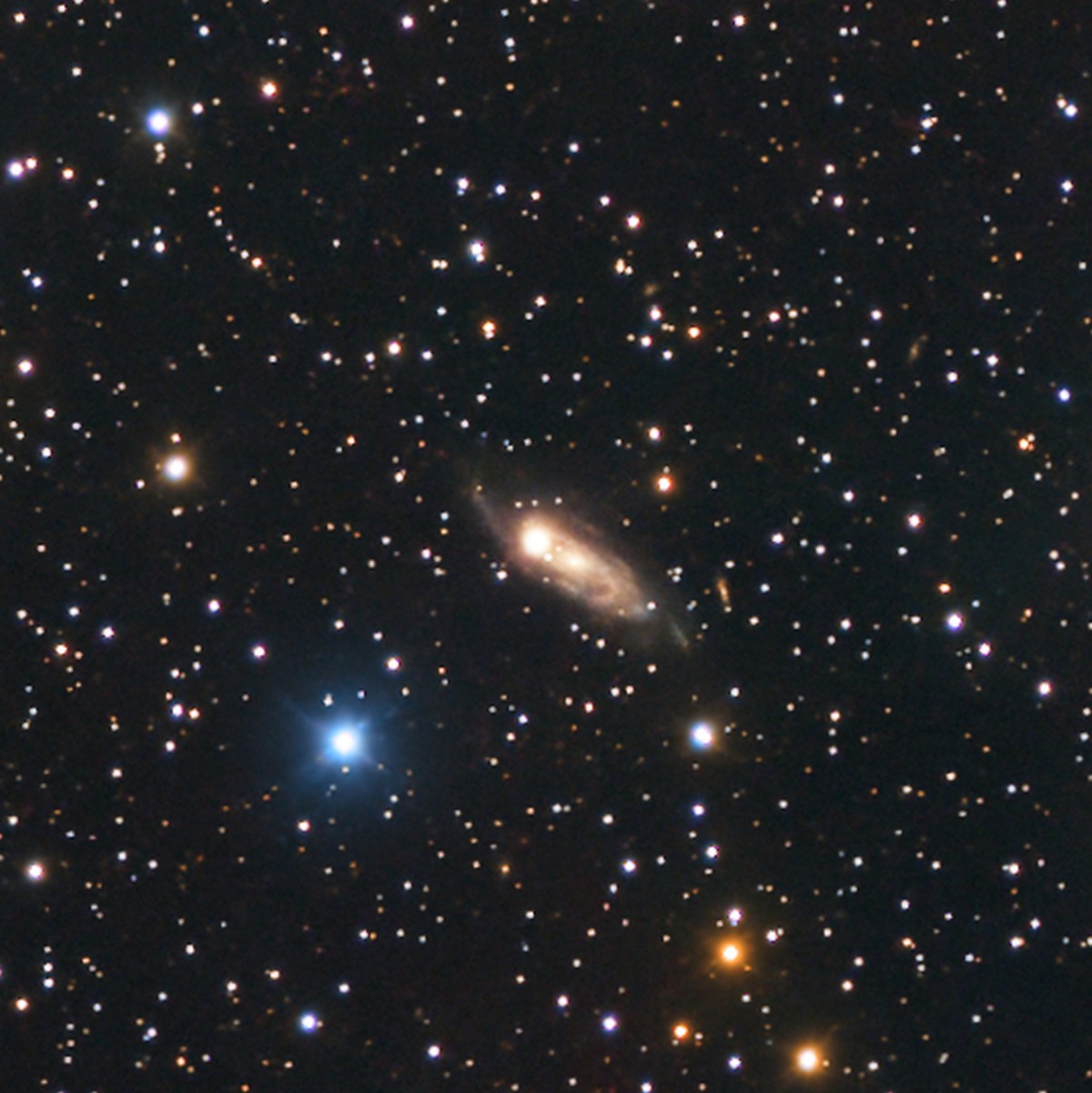 PGC 213253 : une lointaine galaxie spirale, à des millions d'années-lumière bien au-delà du nuage, saisie au passage par la mosaïque.