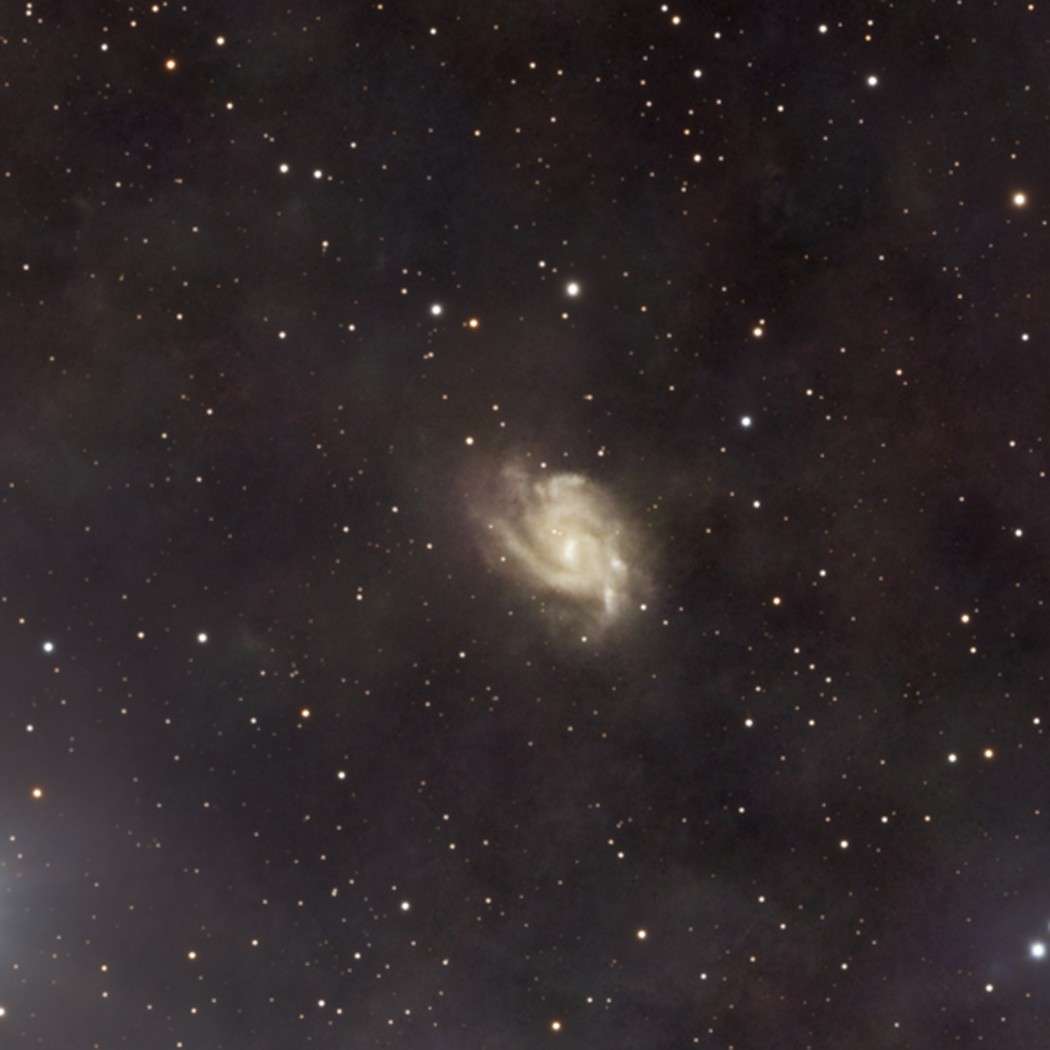 PGC 67671 : une galaxie spirale barrée vue de face, à des millions d'années-lumière bien au-delà du nuage sombre.